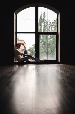 Panoramik pencerenin yanında gömlek ve güneş gözlüğü takan çekici bir esmer.