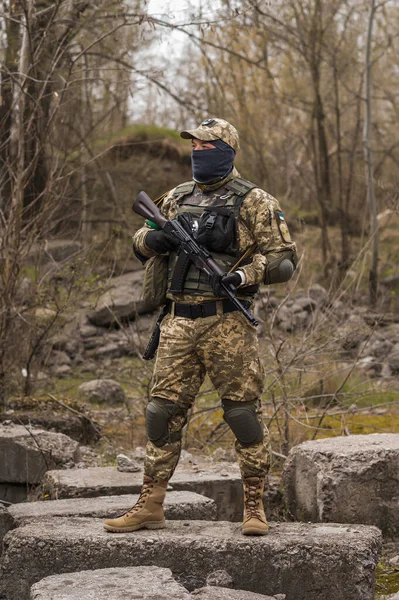 Soldier of the Armed Forces of Ukraine. Military man in tactical uniform with a machine gun in his hands