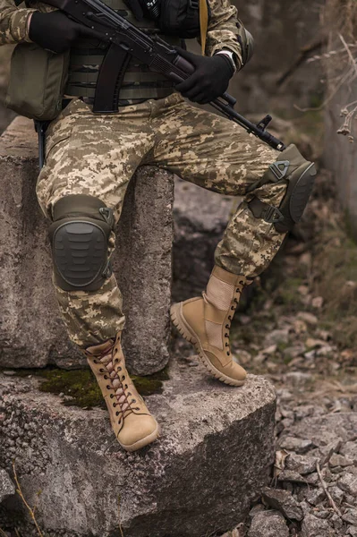 ウクライナ軍の兵士 戦術的な制服を着た軍の男と銃を手に石の上に座っている — ストック写真