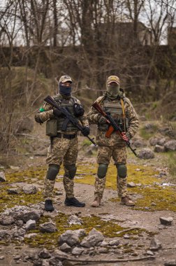 Two Ukrainian soldiers in uniforms aim from a Kalashnikov assault rifle
