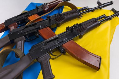 Three loaded Kalashnikov 74 assault rifles on the blue and yellow flag of Ukraine