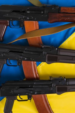 Three loaded Kalashnikov 74 assault rifles on the blue and yellow flag of Ukraine