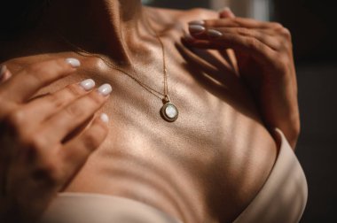 Genç bir kızın yakasında yuvarlak taşlı bir kolyeyle zincirlenmiş.