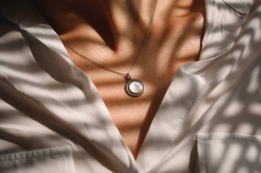 Güzel bir kızın boynunda taş olan gümüş bir kolye.
