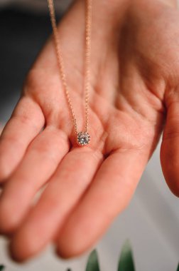 Altın bir kolye ve genç bir kızın ellerinde bir elmas