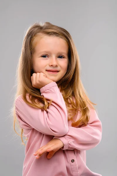 ピンクのセーターとジーンズを着たかわいいブロンドの女の子がスタジオの白いキューブにいます 肖像画 美少女 — ストック写真