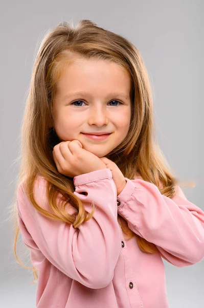 ピンクのセーターとジーンズを着たかわいいブロンドの女の子がスタジオの白いキューブにいます 肖像画 美少女 — ストック写真