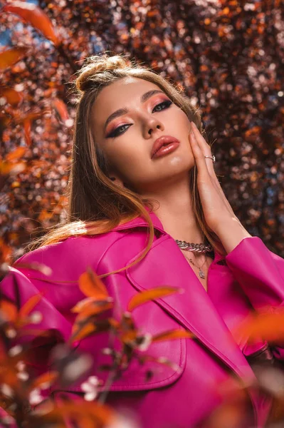 魅力的なフェアヘアウクライナの女の子でピンクの革コートで開花春の木 — ストック写真
