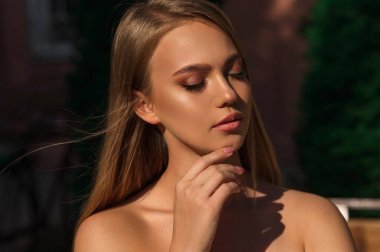 Yeşil bahçedeki doğal makyajlı güzel sarışın kadın.