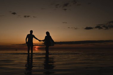 Okyanus kenarında günbatımının arka planında romantik bir çift. Gün batımı okyanus boyunca yürür