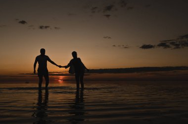 Okyanus kenarında günbatımının arka planında romantik bir çift. Gün batımı okyanus boyunca yürür