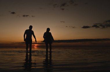 Okyanus kenarında günbatımının arka planında romantik bir çift. Gün batımı okyanus boyunca yürür