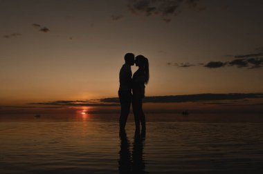 Okyanus kenarında günbatımının arka planında romantik bir çift. Gün batımı okyanus boyunca yürür