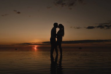 Okyanus kenarında günbatımının arka planında romantik bir çift. Gün batımı okyanus boyunca yürür