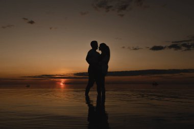 Okyanus kenarında günbatımının arka planında romantik bir çift. Gün batımı okyanus boyunca yürür