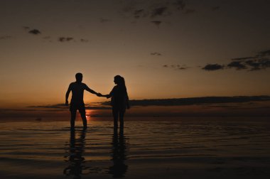 Okyanus kenarında günbatımının arka planında romantik bir çift. Gün batımı okyanus boyunca yürür
