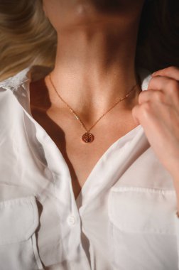 Beyaz ipek bluzlu narin ve şehvetli bir sarışın ve boynunda bir süslemeyle.