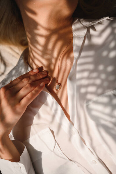 Нежная и чувственная блондинка в белой шелковой блузке и с украшением на шее