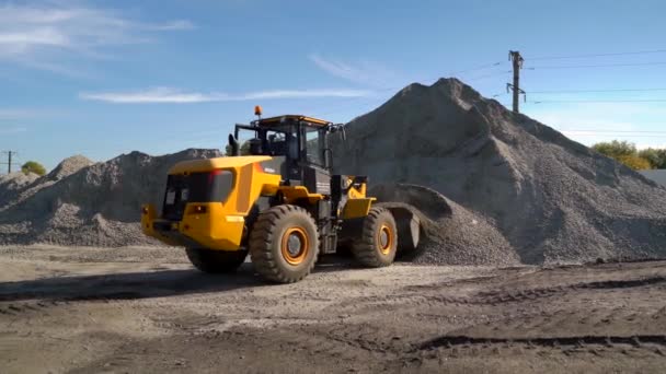 UCRANIA. Grandes pilas de piedras trituradas y arena al aire libre. Bulldozer trabajando en el territorio de la planta de asfalto en un día soleado. — Vídeo de stock