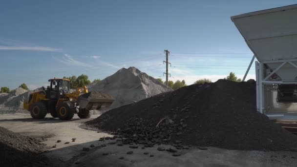 Steenbreker steenbreker steenbreker machine bij open put mijnbouw en verwerking fabriek voor gemalen steen, zand en grind. Trekker drijft hopen grind op plant. — Stockvideo