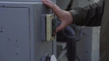 İşçi elleri düğmelere basıyor, kontrol panelini açıyor. Yakın çekim.