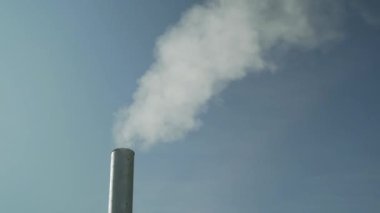 Duman bitkinin bacasından geliyor. Çatıdaki boru. Baca. Köy evi. Bacalı bir ev. Mavi gökyüzünde duman. 