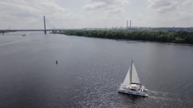 Hava manzaralı beyaz yelkenli tekne nehirde yüzüyor. Yeşil ağaçlı manzara