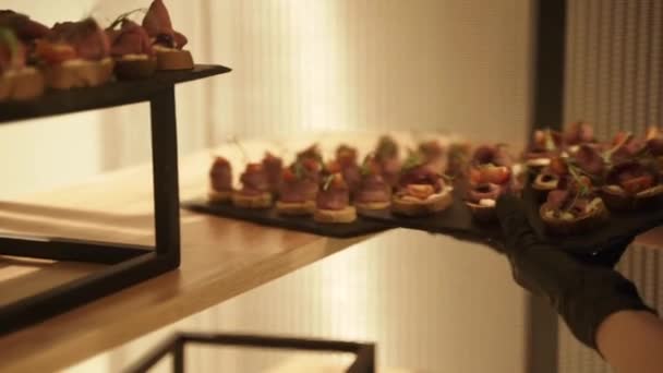 Ober zet snacks gerechten op het versierde buffet, close-up — Stockvideo