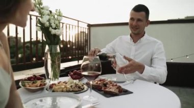 Gün batımında çatıda buluşalım. Genç adam ortağını büyülüyor. Çatıda romantik bir akşam yemeği