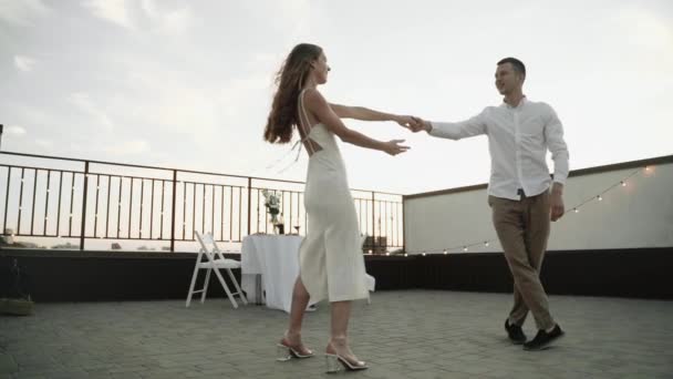 Gün batımında çatıda dans eden genç çift, süper yavaş çekim. — Stok video