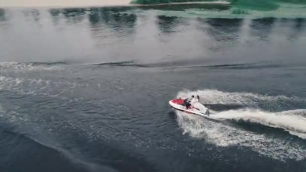 Imágenes aéreas siguiendo a una pareja montada en una moto acuática en el río — Vídeo de stock