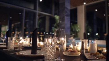 Mumları gözlüklerle yakmak. Mum alevi. Şarap bardakları. Masanın üzerindeki dekorasyon..