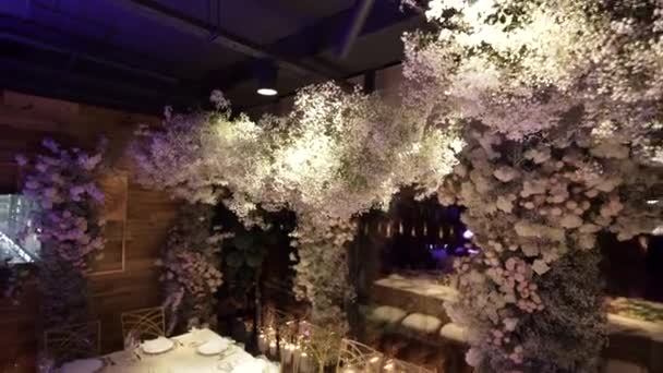 Salle de restaurant décorée de fleurs fraîches au plafond. Salle d'organisation de l'événement — Video