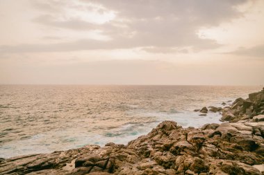 Deniz ve kayaların üzerinde gün batımı manzarası