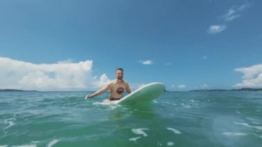 Adam okyanusta dalgalarda sörf yapıyor, yakın plan.