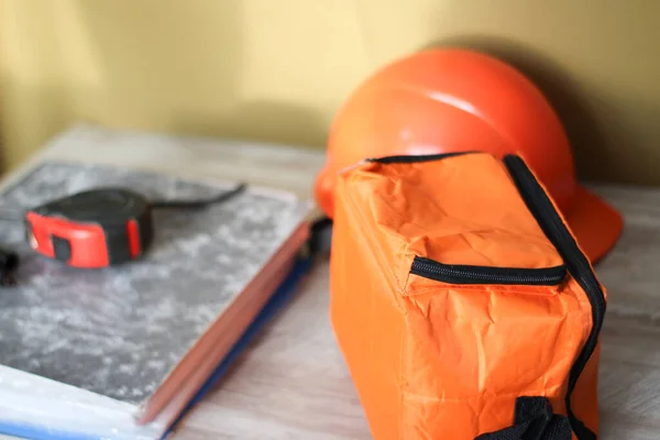 橘色袋卡尺和建筑用头盔放在桌子上 — 图库照片