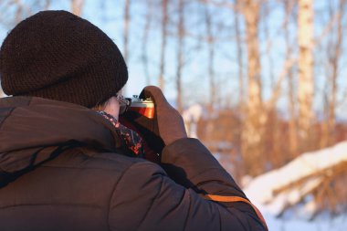 young woman with old camera shooting winter landscape