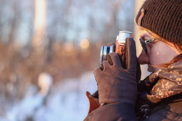 young woman with old camera shooting winter landscape