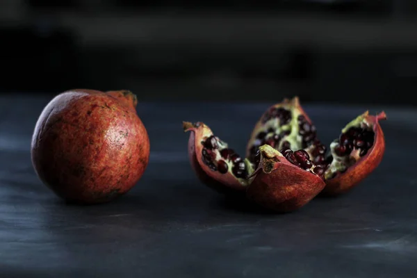 Masanın üzerinde kırık bir nar var.