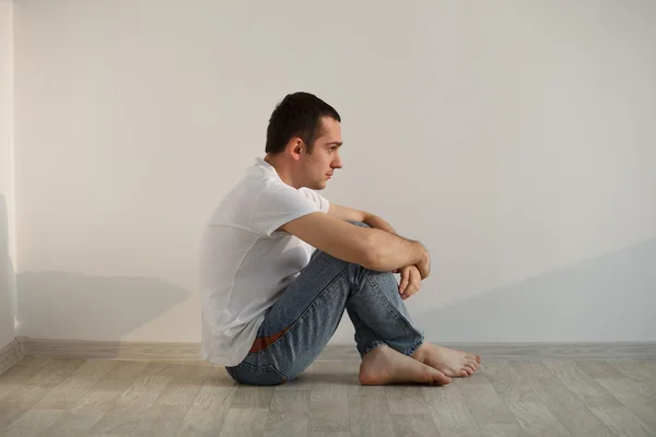 Schöner junger Mann sitzt auf dem Fußboden — Stockfoto