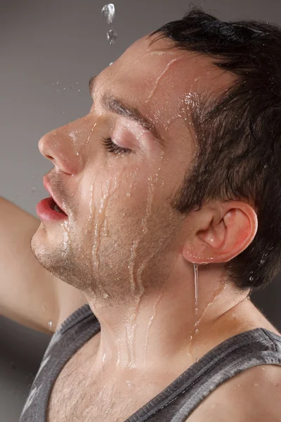 Jovem e feliz cara derramando água em seu — Fotografia de Stock