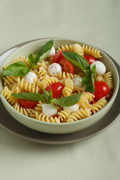 Salada de macarrão com tomates cereja e folhas de manjericão — Fotografia de Stock