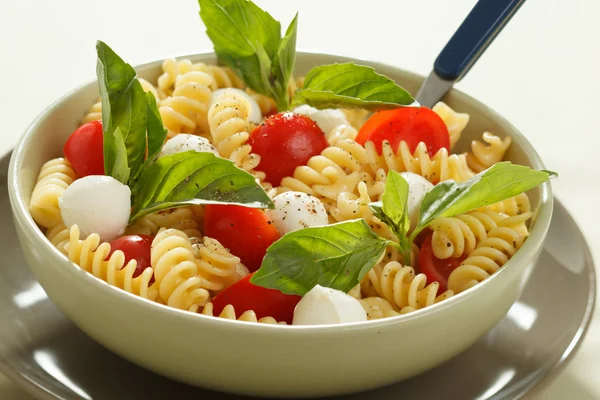 Salada de macarrão com tomates cereja e folhas de manjericão — Fotografia de Stock