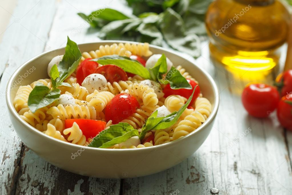 Pasta salad with cherry tomatoes and basil leaves