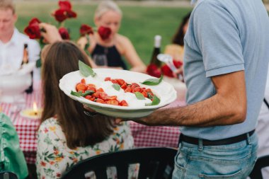 Buratta cheese and tomatoes in a bowl. Decorated with pine nuts. Selective focus.