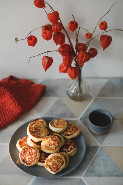 Frühstück mit hausgemachten Quark-Pfannkuchen, einer Tasse Tee und Blumen in einer Vase auf dem Tisch — Stockfoto