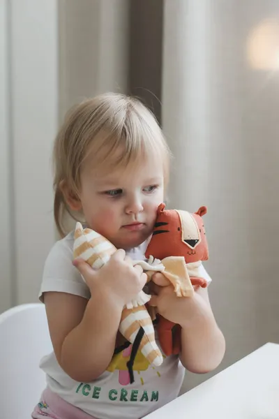 Niña jugando con divertido juguete tigre pequeño, símbolo de nuevo 2022 en una guardería soleada — Foto de Stock