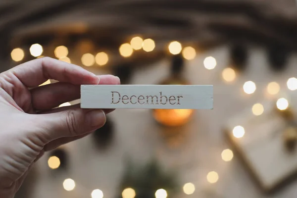 Slovo prosinec v kalendáři podle pozadí se smrkovými větvemi a zářící girland. Vánoce, zima, koncept nového roku — Stock fotografie