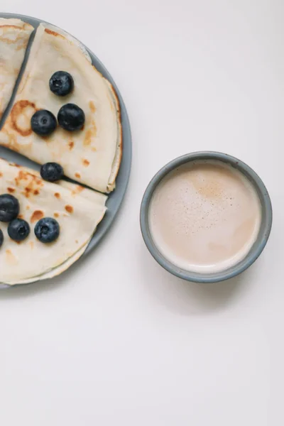 Sarapan lezat dengan pancake dengan blueberry di atas meja putih dan secangkir kopi — Stok Foto
