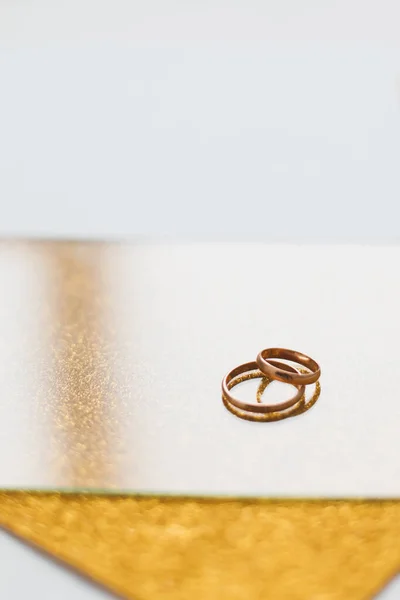 Duas alianças de casamento douradas num fundo dourado. Um convite de casamento. presente valentine, modelo de banner de compras de venda, espaço de cópia — Fotografia de Stock